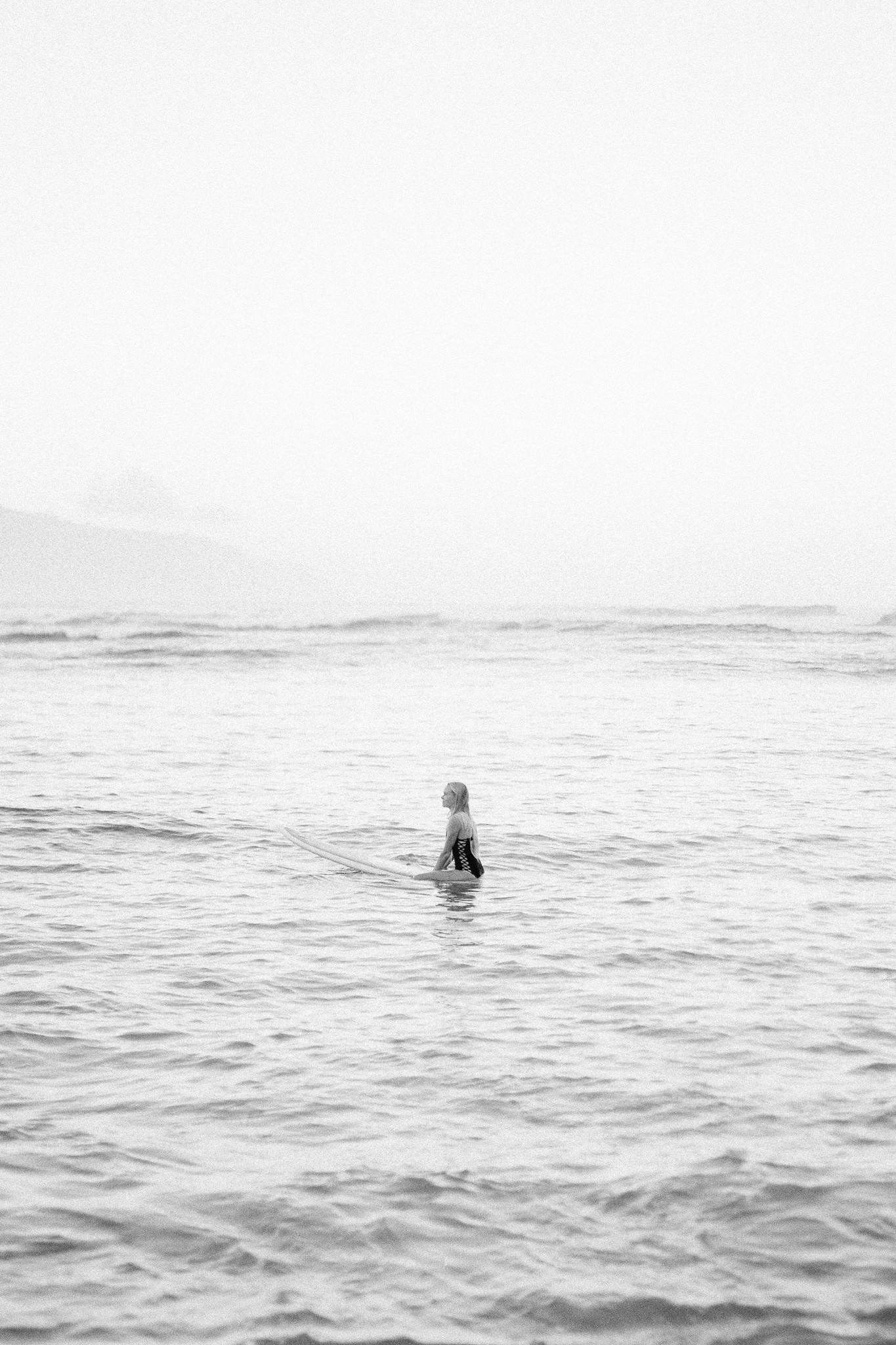 film photo of oahu hawaii surfer girl sitting in ocean on surfboard lifestyle portraits